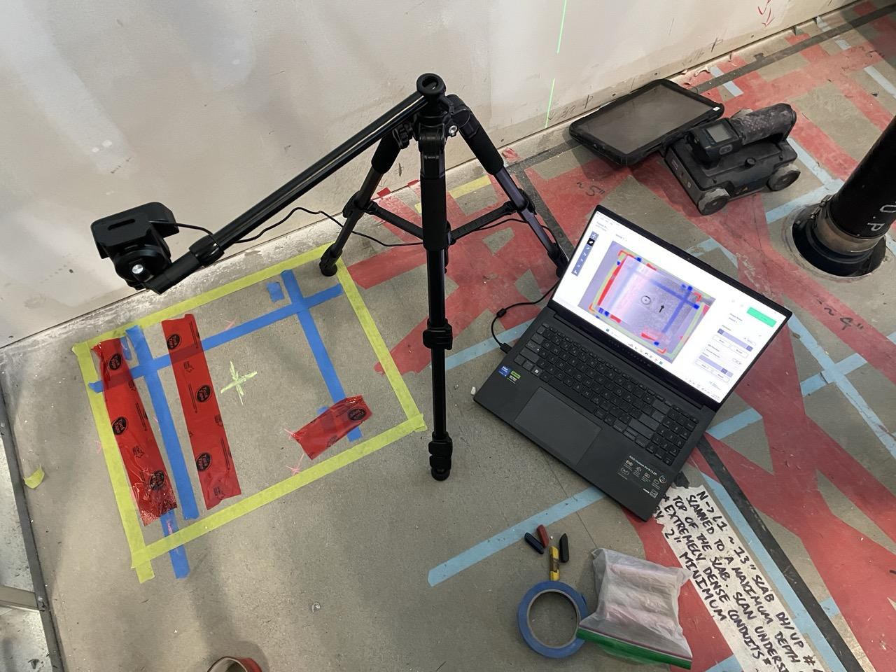 AR Preview job site setup: a tripod-mounted webcam pointed at a marked slab with the reference marker visible, the laptop running Radii-x software next to it — the only added gear beyond the standard X-Ray kit