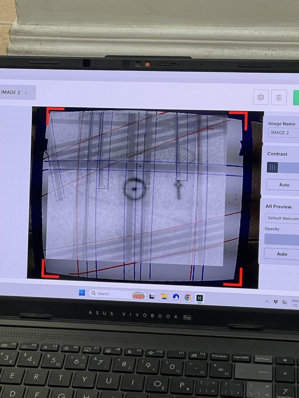 Close-up of the laptop on a slab during marking: the AR Preview overlay clearly shows rebar and a conduit element directly on top of the live camera view of the concrete surface